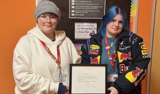 Two Animal Care students holding the framed letter from Sir David Attenborough