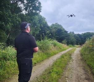 Police officer flying a drone over a wooded area